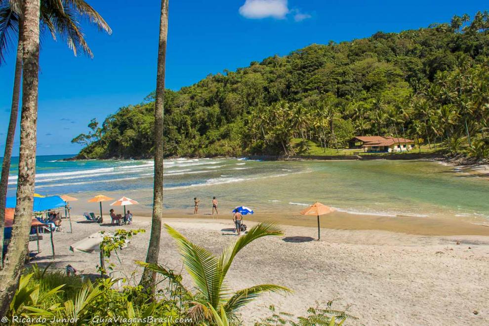 Imagem de pessoas nos guarda sol da Praia de Jeribucaçu.